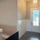 An entryway features white wainscoting on beige walls